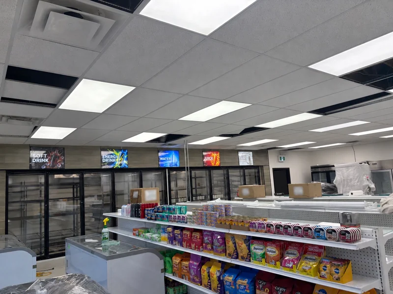 LED drink-category signs above retail refrigerators during a Winnipeg store fit-out